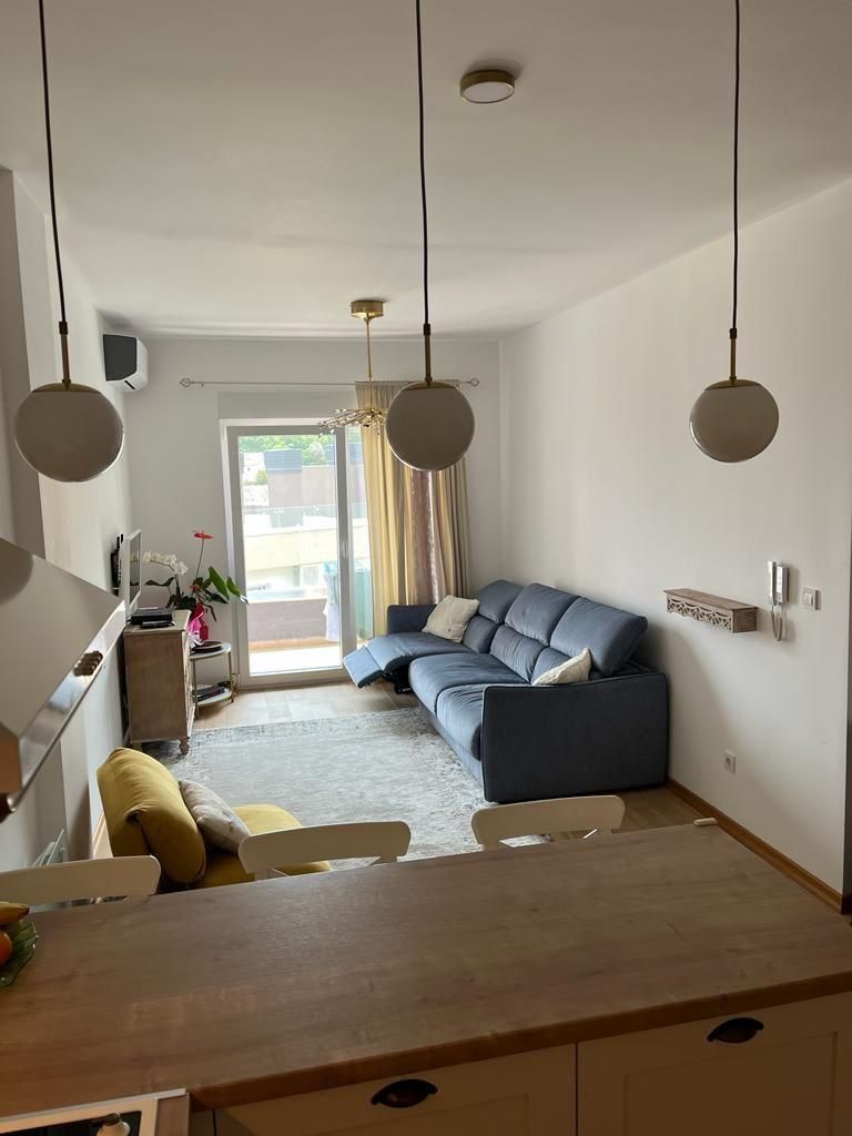 dc1832f2-8c04-41b2-ab29-eb0ebfd89e40 Dnevni boravak jednosobnog stana u Budvi sa plavom garniturom i izlazom na balkon