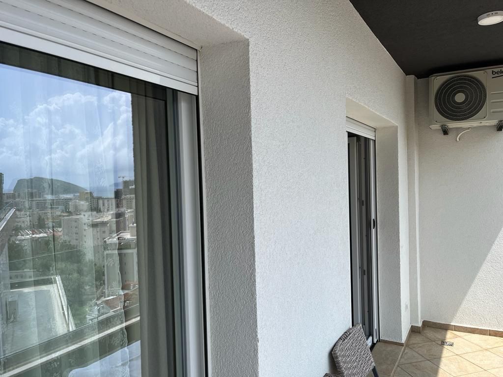 aec69f44-0e39-4a93-9854-b387b2c87c51 Balkon stana u Budvi sa pogledom na grad i klima uređajem na zidu