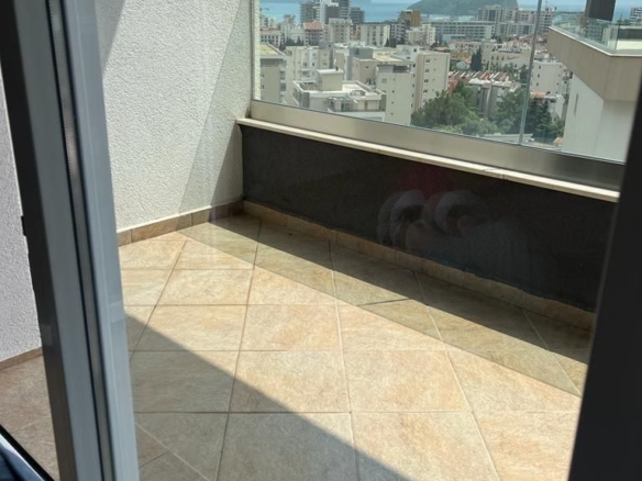 Dnevni boravak jednosobnog stana u Budvi sa plavom garniturom i izlazom na balkon – fotografija 7