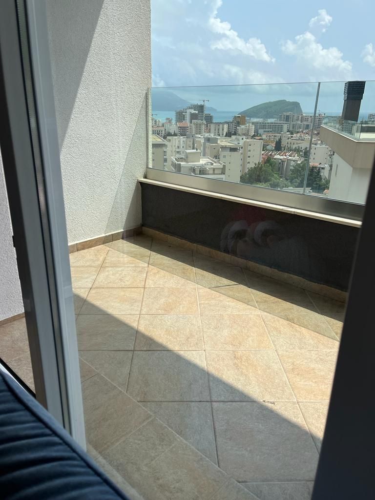 659a0e6b-f7ac-47e4-8d04-5ade4312bb31 Dnevni boravak jednosobnog stana u Budvi sa plavom garniturom i izlazom na balkon – fotografija 7