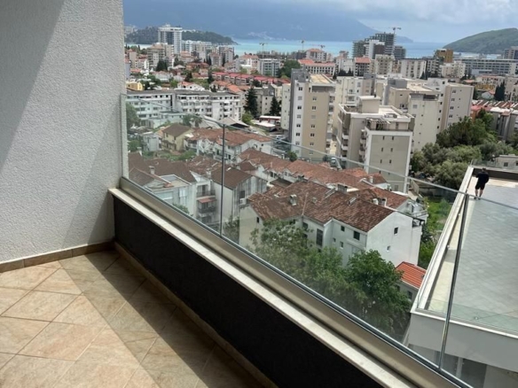 Dnevni boravak jednosobnog stana u Budvi sa plavom garniturom i izlazom na balkon – fotografija 8
