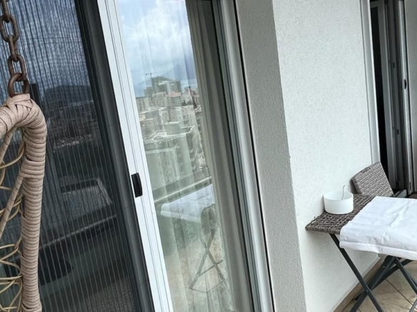 Dnevni boravak jednosobnog stana u Budvi sa plavom garniturom i izlazom na balkon – fotografija 10
