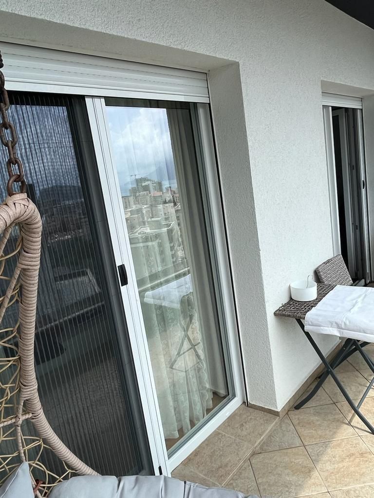 fc927b3d-6740-4bad-a4a2-1a367ba68788 Dnevni boravak jednosobnog stana u Budvi sa plavom garniturom i izlazom na balkon – fotografija 10